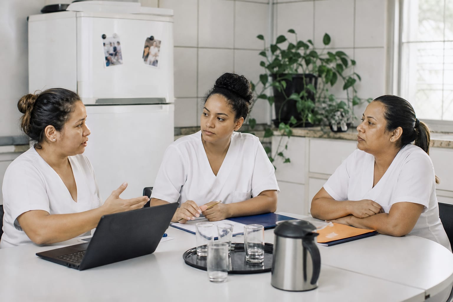 Equipe de coordenação de uma empresa de home care em reunião numa sala clara com quadro branco vazio